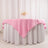 Pink tablecloth draped over a round table with floral centerpiece.
