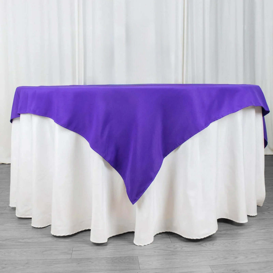 Purple tablecloth draped over a white table for elegant decor.