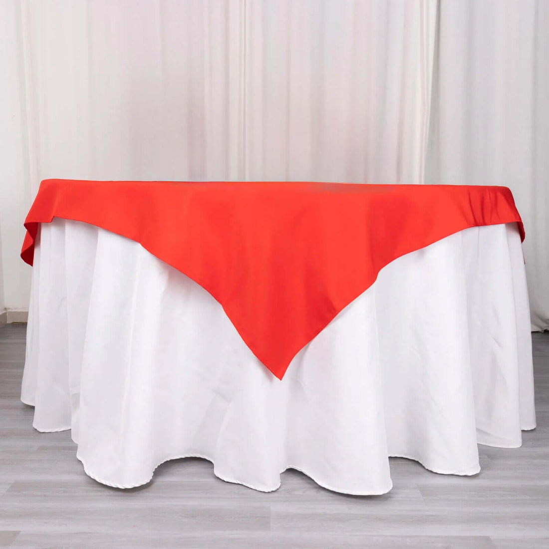 Red tablecloth draped over a white table for elegant dining decor.