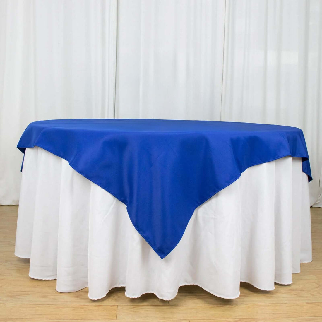 Blue tablecloth with white underlayer, elegantly draped on a round table.