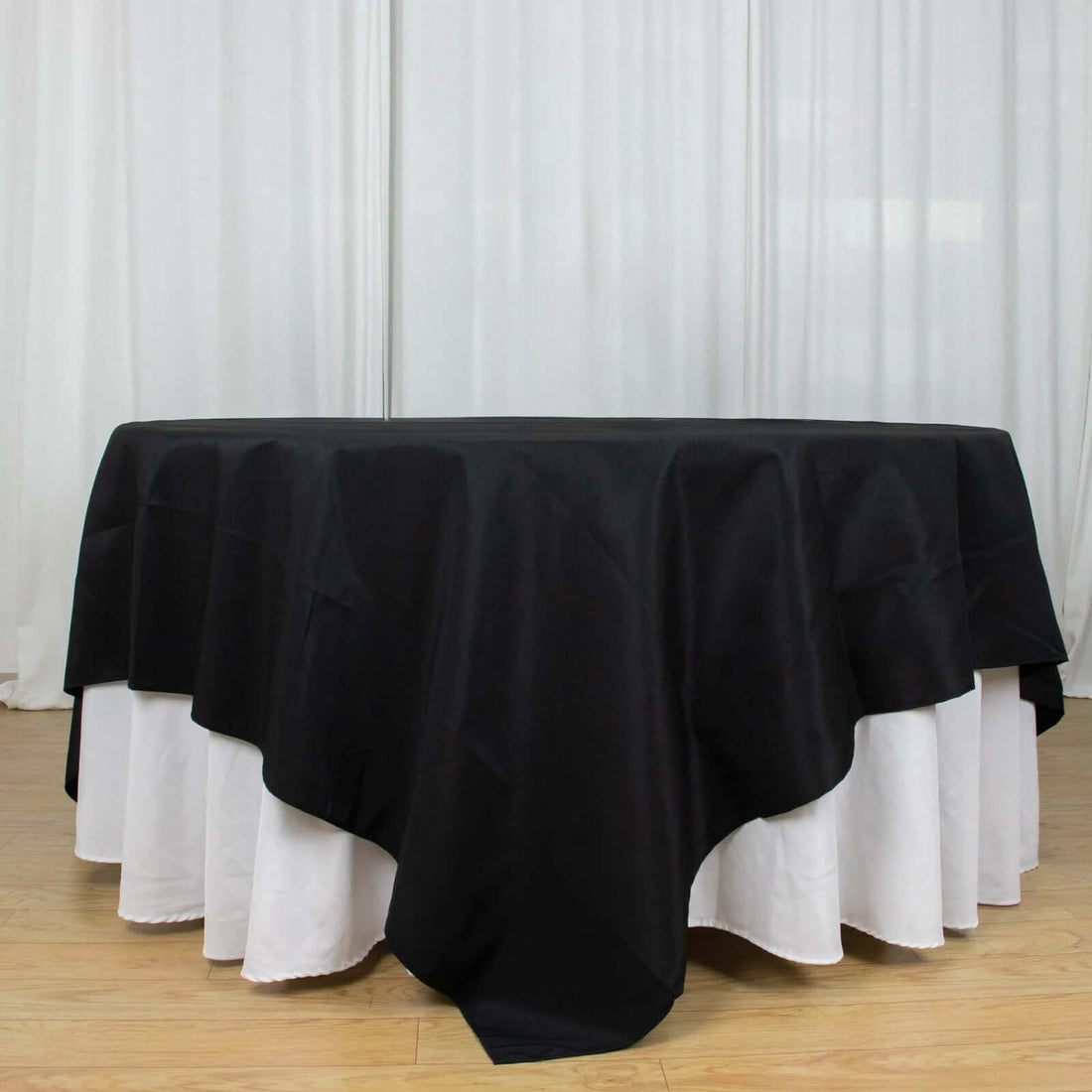 Black tablecloth with white underlay for elegant dining setups.