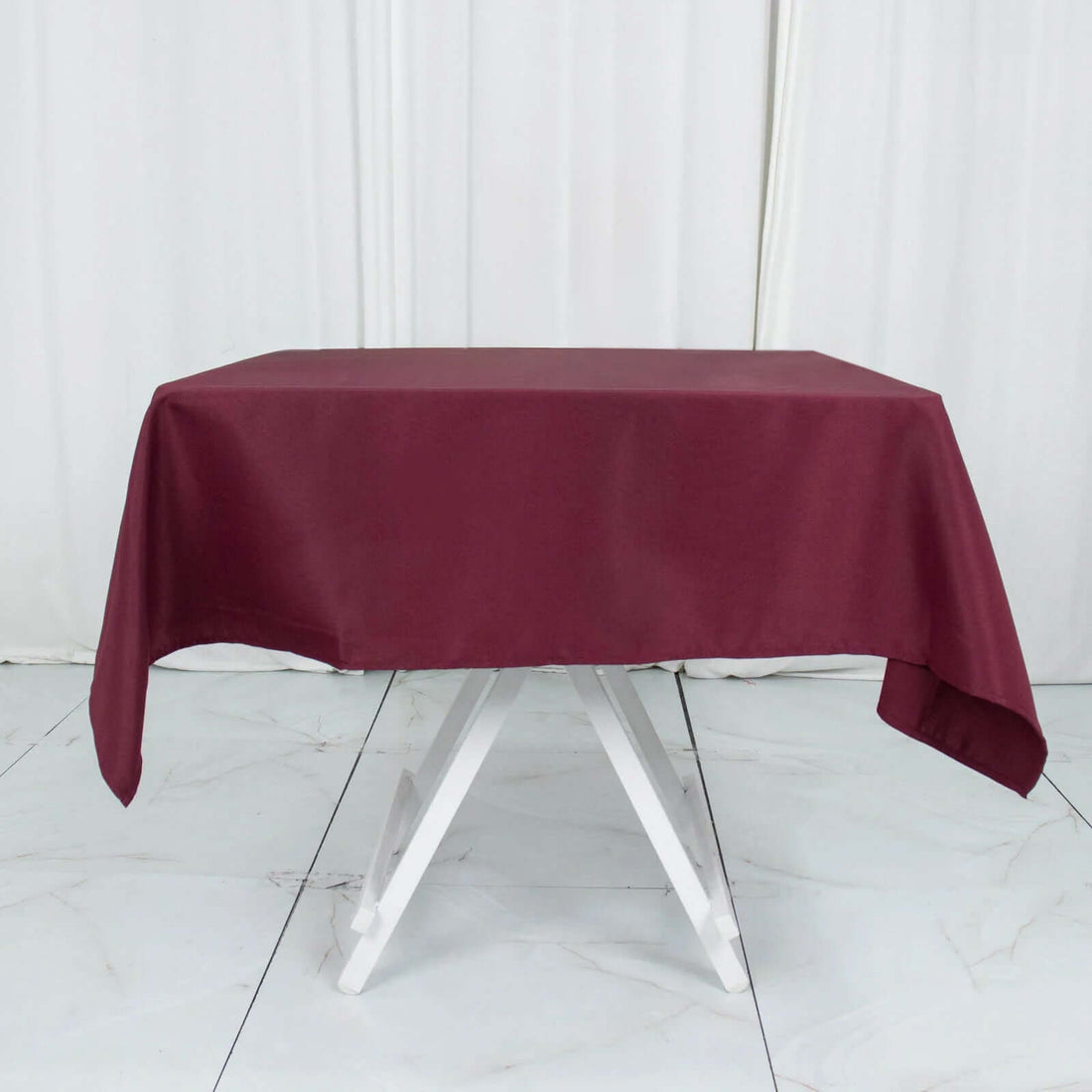 Burgundy tablecloth draped over a white folding table