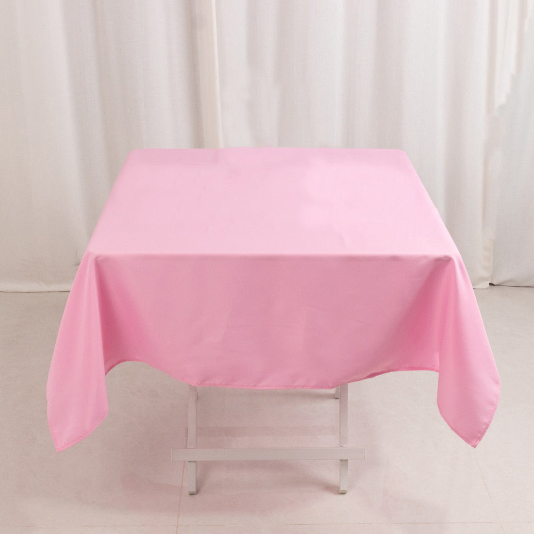 Pink tablecloth draped over a folding table in a studio setting.