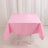 Pink tablecloth draped over a folding table in a studio setting.