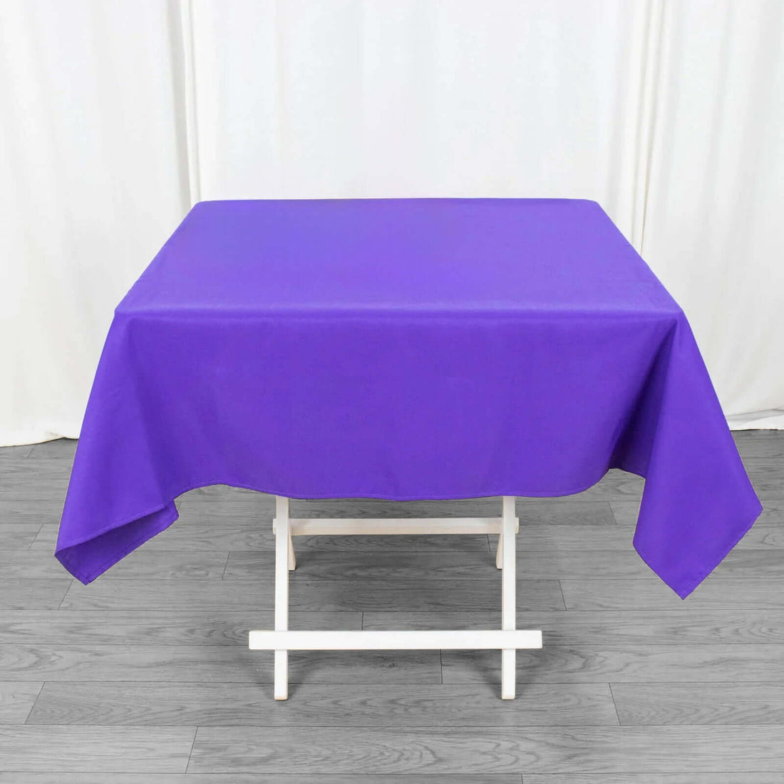 Purple tablecloth draped over a white folding table.