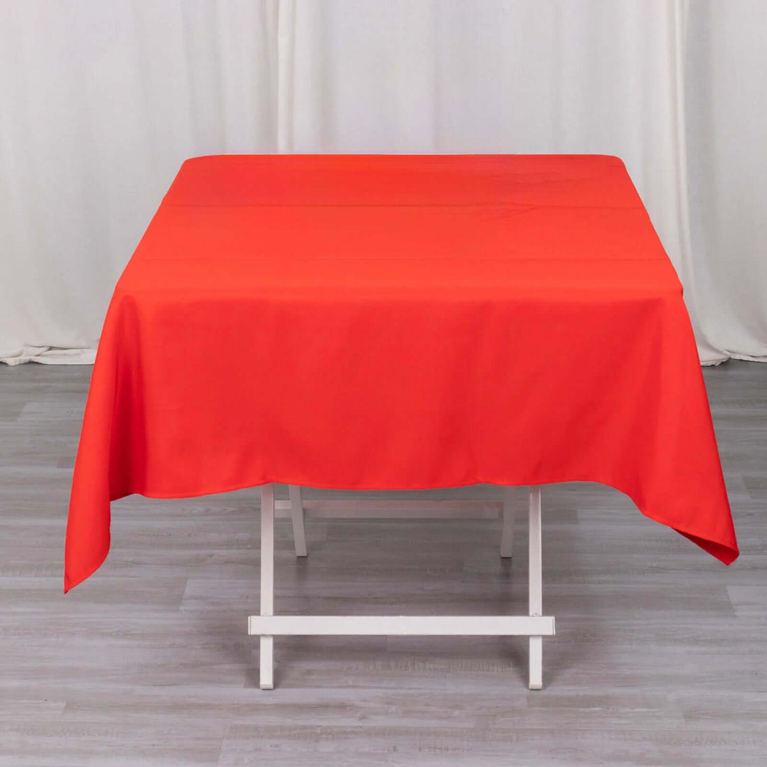 Red tablecloth draped over a white table in a studio setting.
