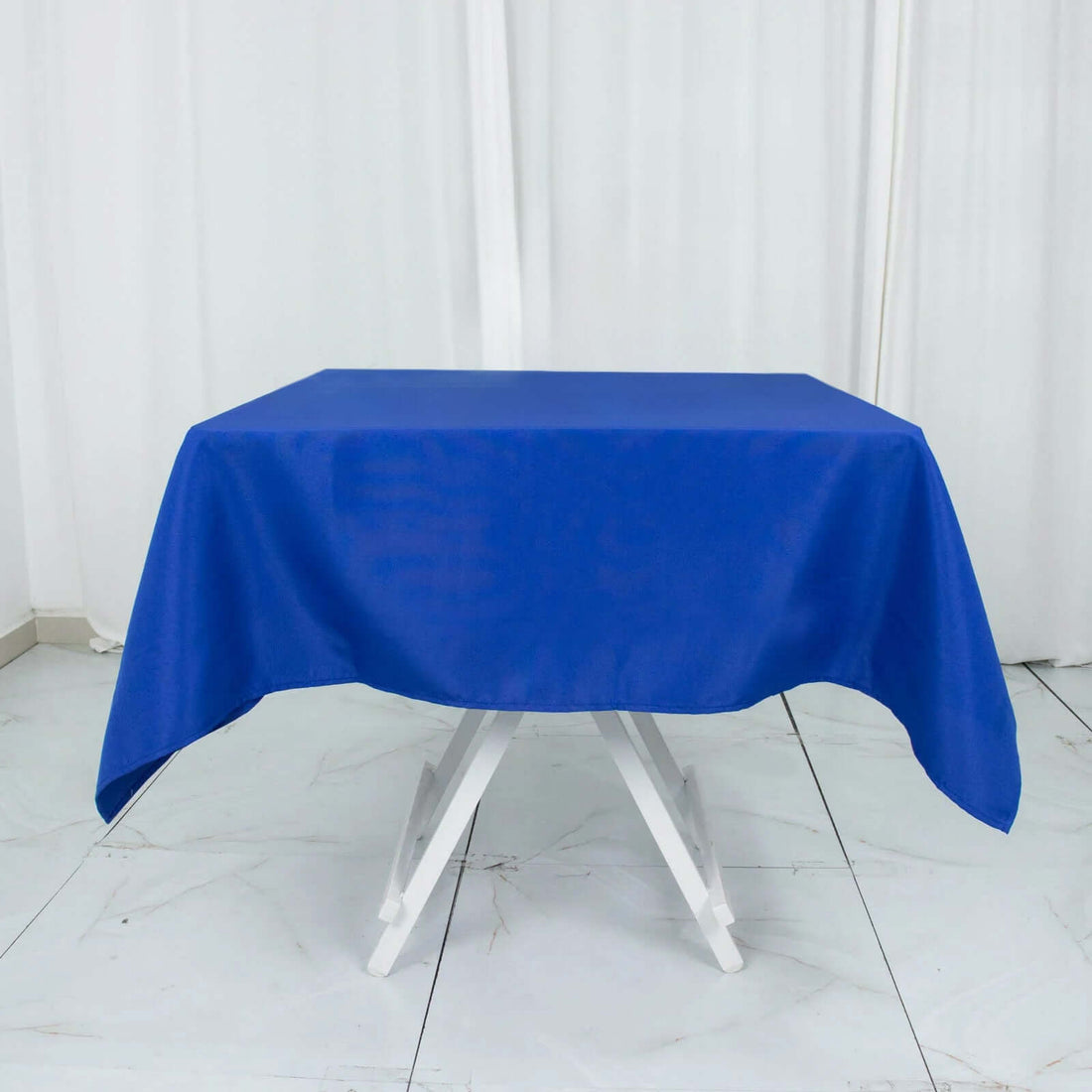 Blue tablecloth draped over a white table against a plain backdrop