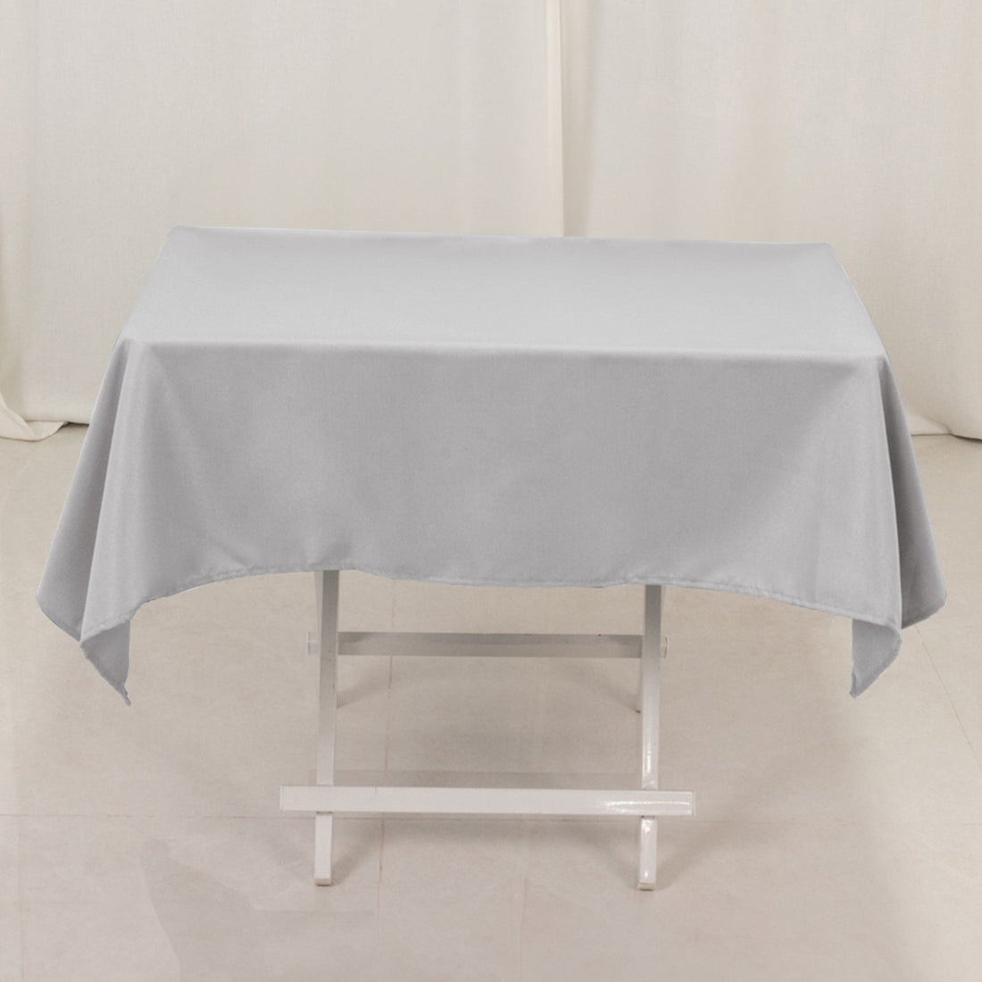 Gray tablecloth draped over a white folding table