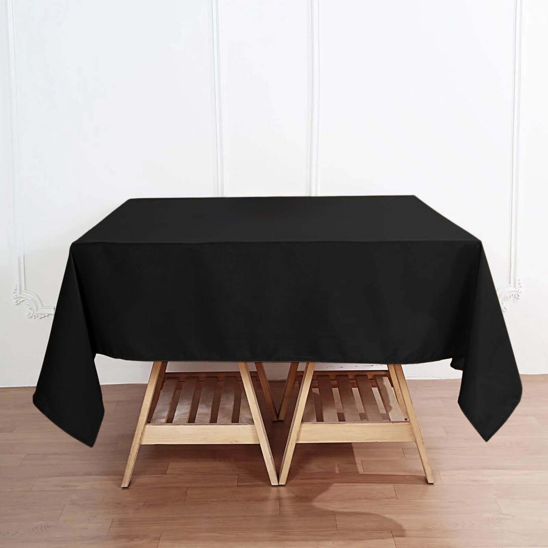Black tablecloth draped over a wooden table in a styled interior setting.