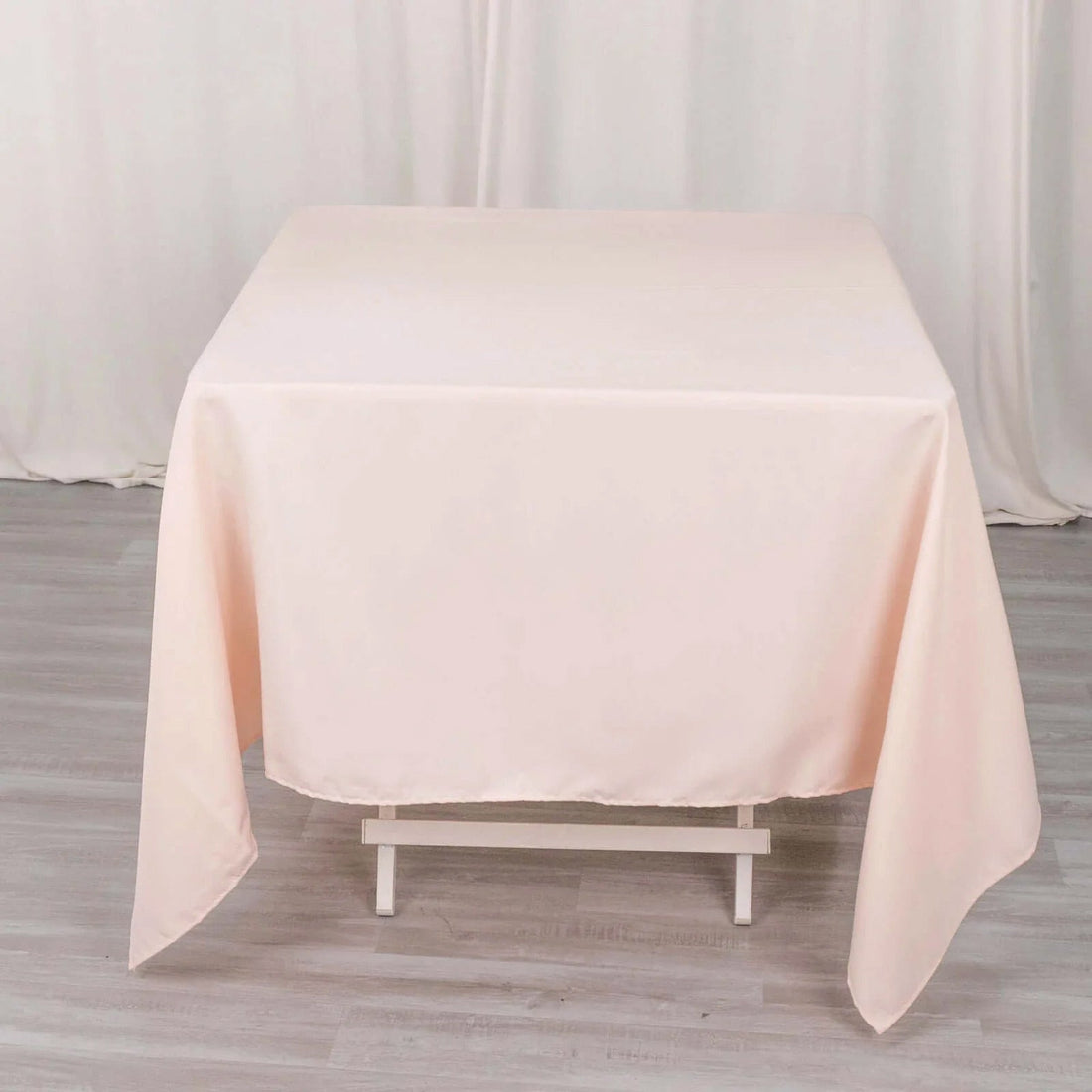 Peach tablecloth draped on a white table in a studio setting