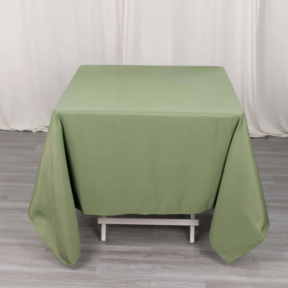 Green tablecloth draped over a white table in a studio setting.