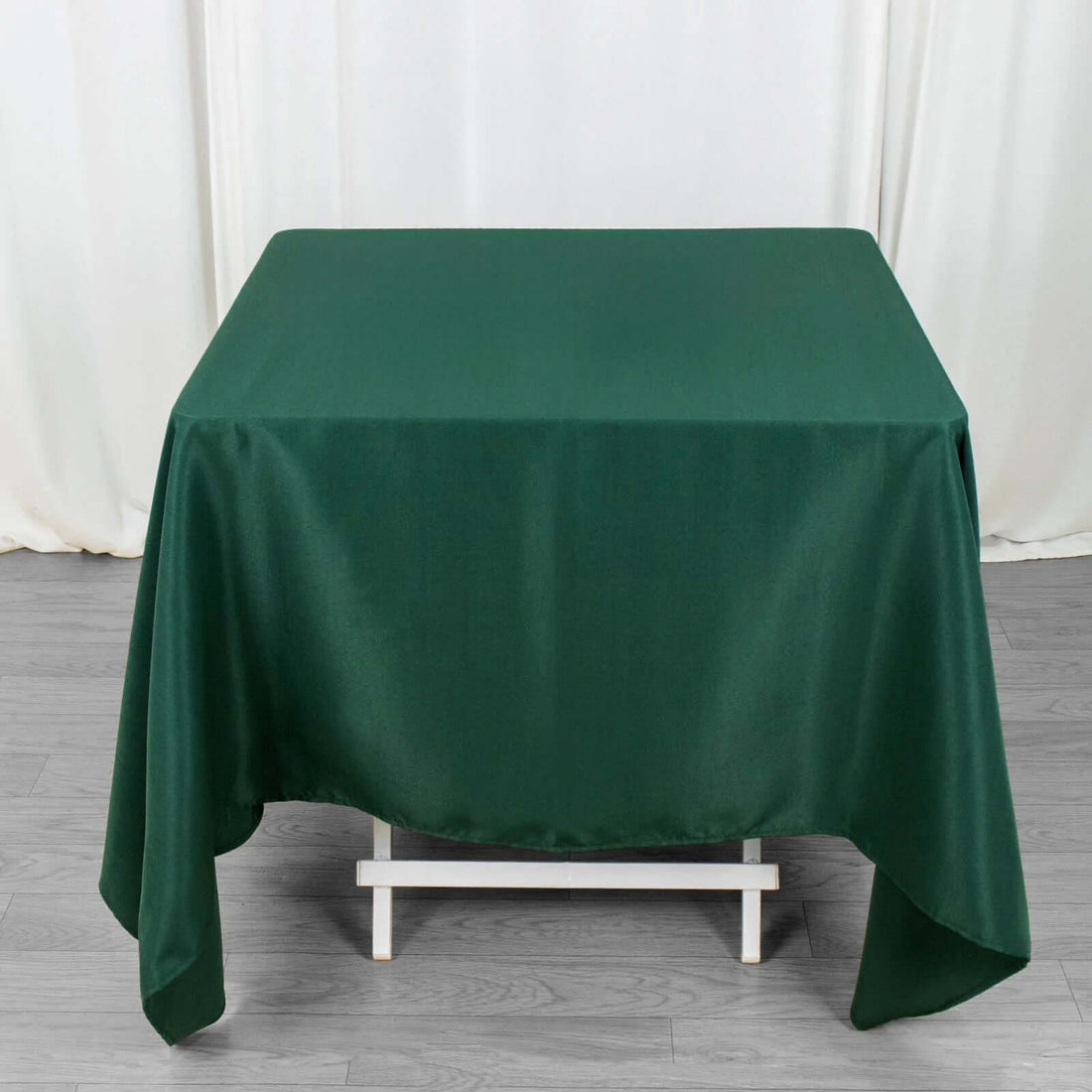 Green tablecloth draped over a table with a plain backdrop.