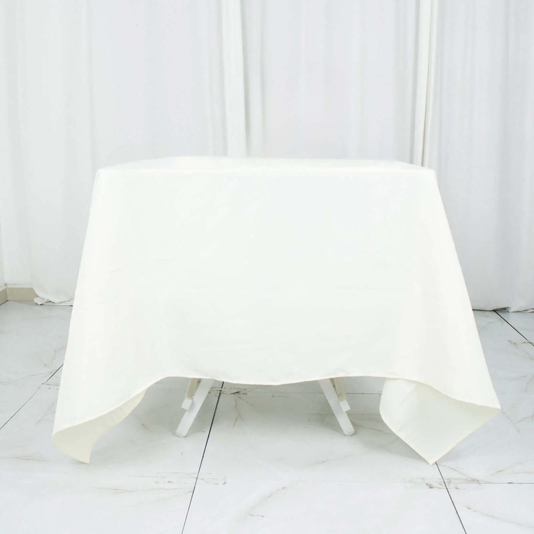 White tablecloth draped over a folding table in a studio setting