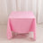 Pink tablecloth draped over a table in a studio setting.