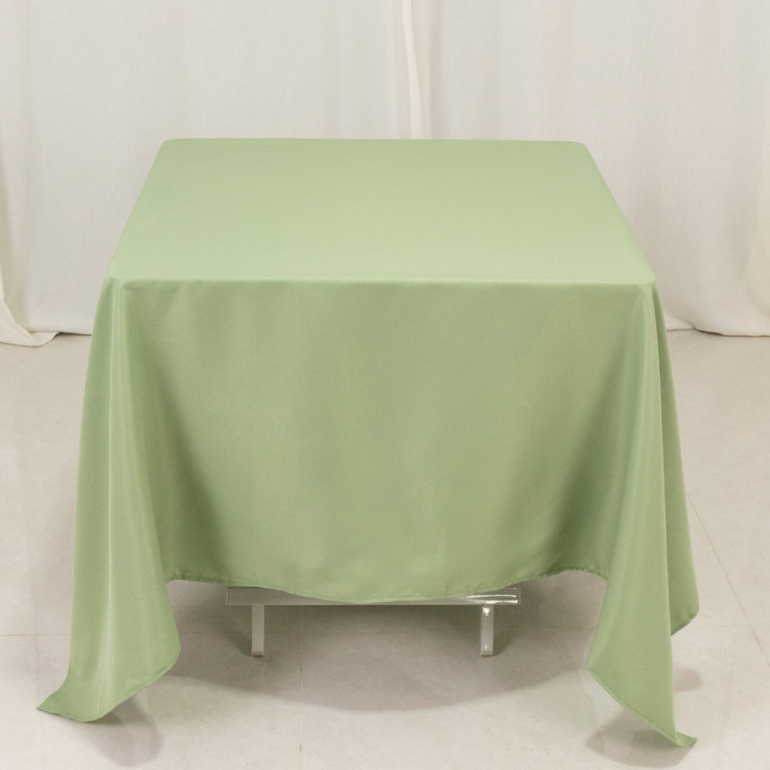 Green tablecloth draped over a square table, showcasing smooth fabric texture.