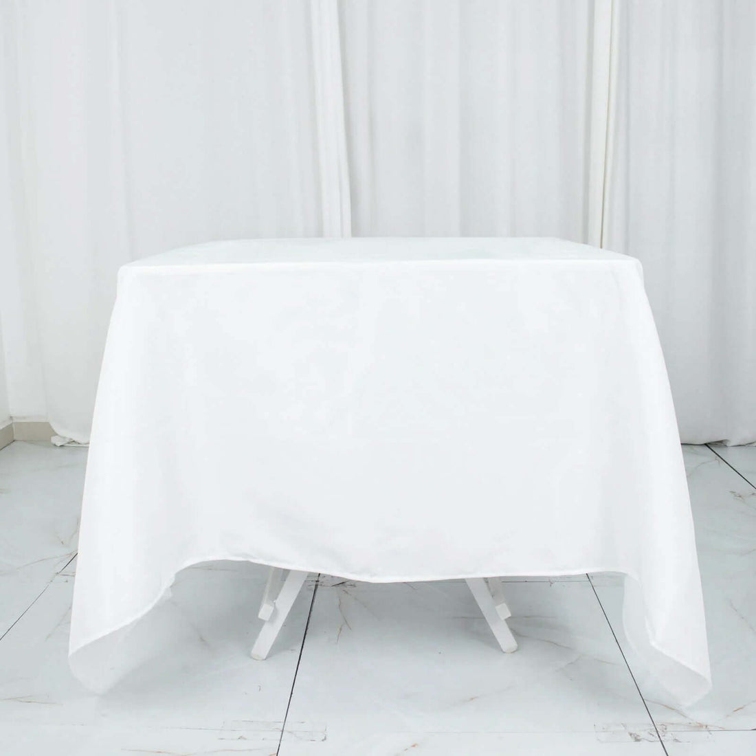 White table covered with a smooth tablecloth in a studio setting.
