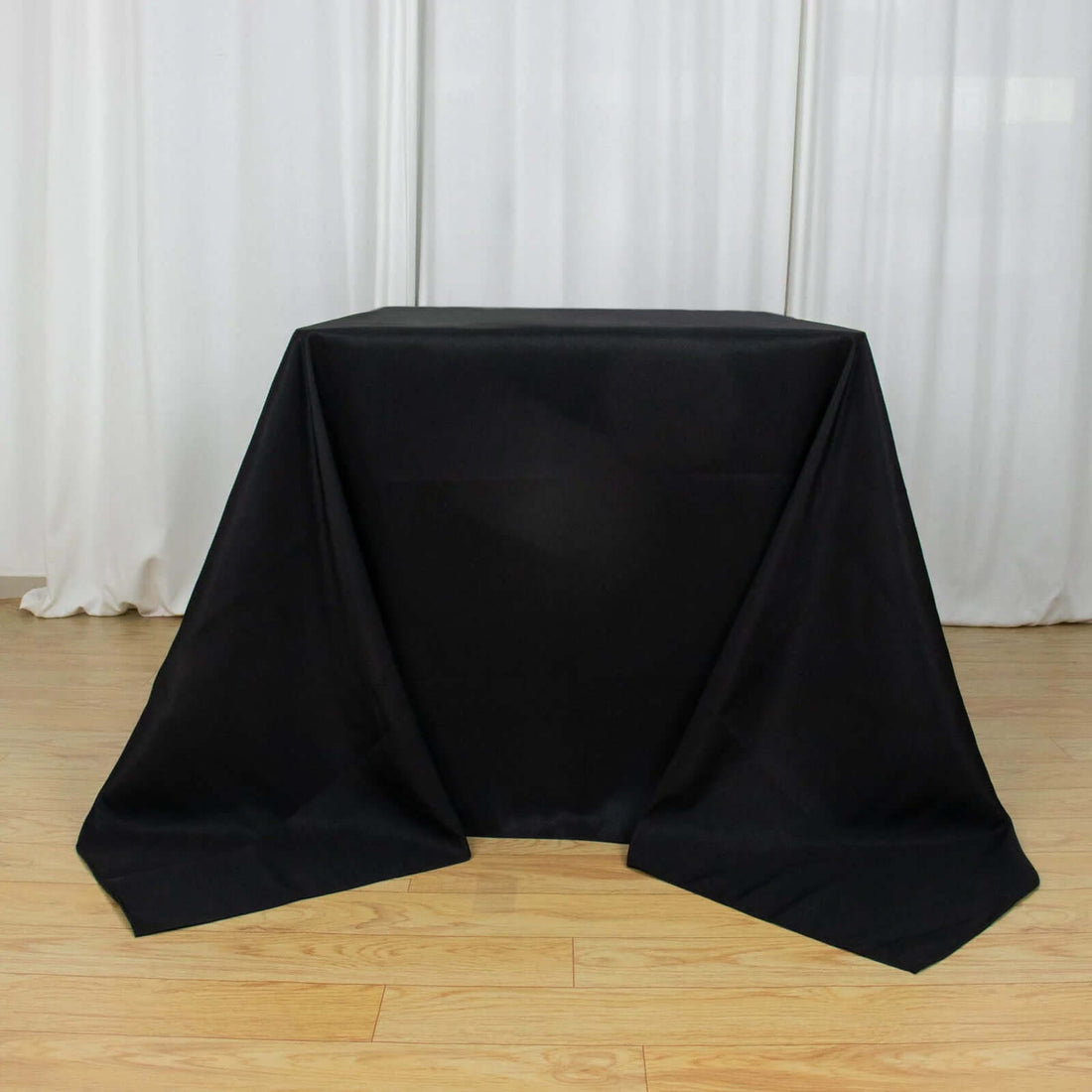 Black table cover draped over a table in a studio setting.