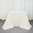 White table with draped fabric on a plain backdrop.