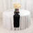Elegant round table set with black runner, plates, and floral centerpiece.