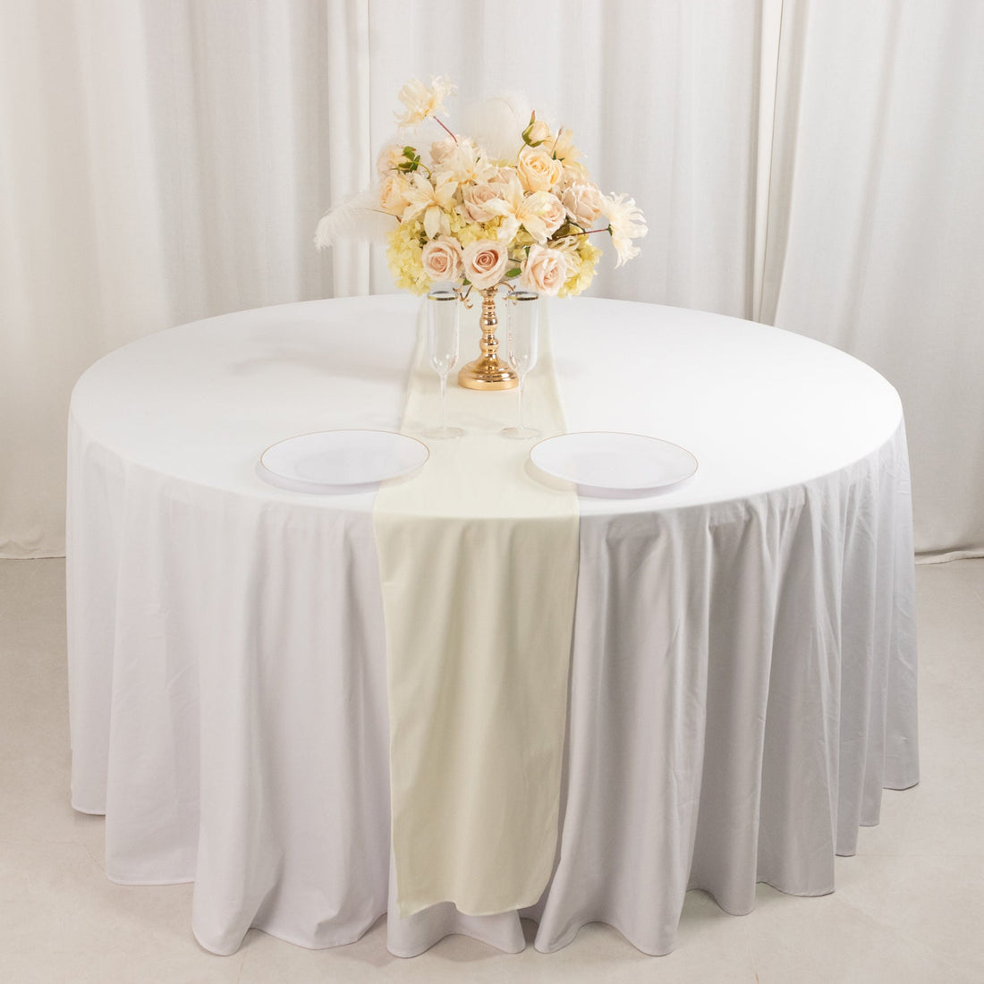 Elegant round table set with white linens and floral centerpiece.