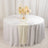 Elegant round table set with white linens and floral centerpiece.