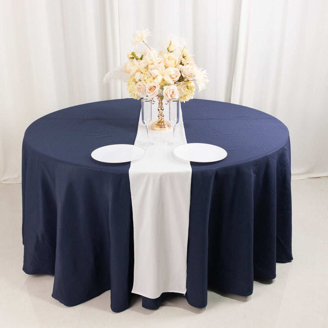 Navy round table with white runner and floral centerpiece in studio setting.