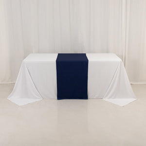 Navy blue table runner on a white tablecloth in a studio setting