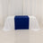 Table with white draping and a blue runner on a plain backdrop.