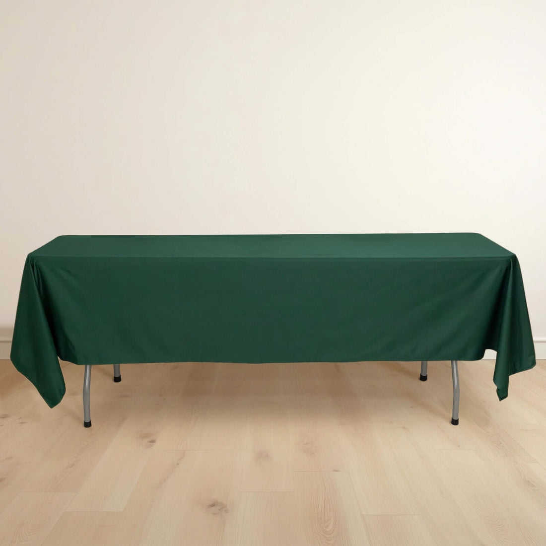 Green tablecloth draped over a table on a light wooden floor.