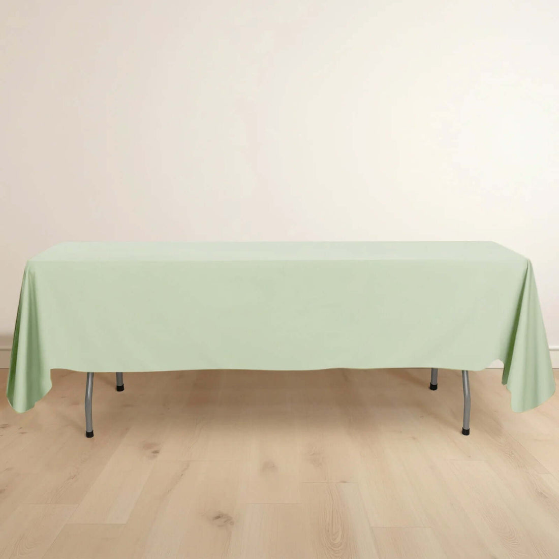 Green tablecloth draped over a table on a light wooden floor.