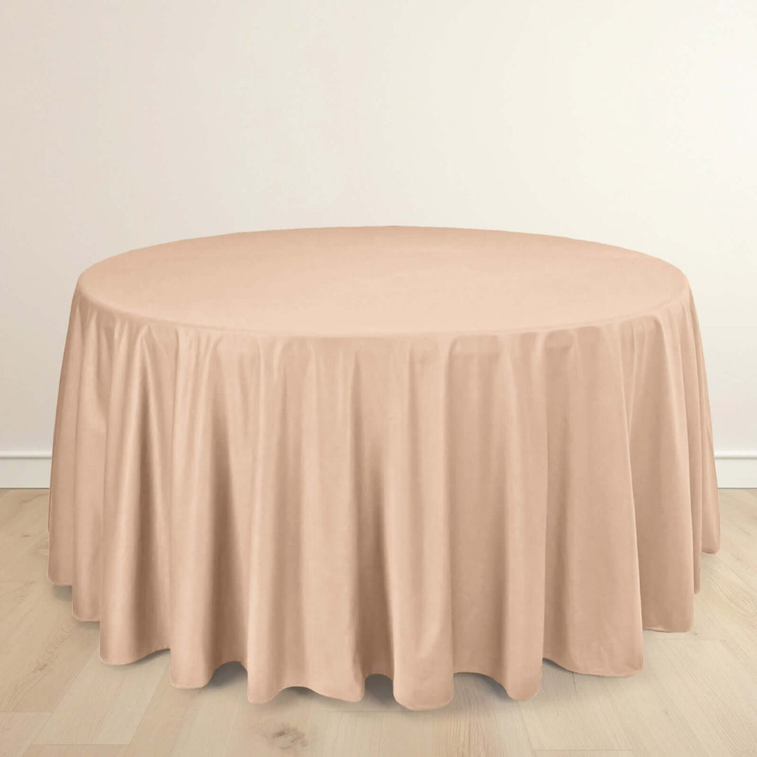 Round beige tablecloth with elegant draping on a plain background.