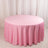 Round pink tablecloth draped over a circular table in a studio setting