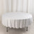 Round white table with a draped tablecloth on a plain backdrop.