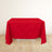 Red tablecloth draped over a white table in a minimalistic setting.