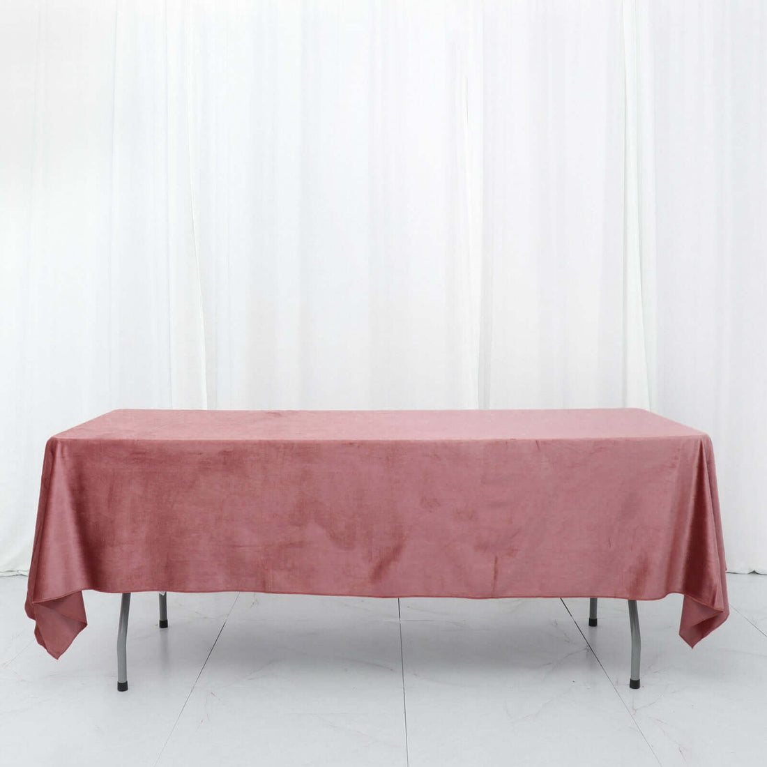 Pink tablecloth draped over a table on a white backdrop.