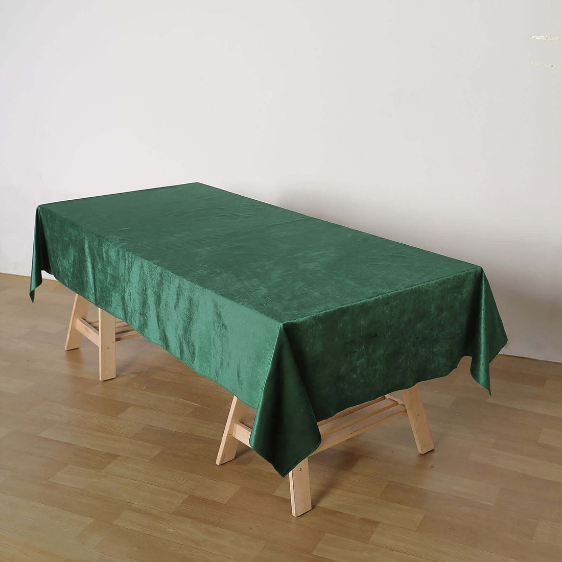 Green tablecloth draped over a wooden table in a minimalistic setting.