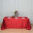 Elegant red tablecloth draped over a table set for dining with flowers and glassware.