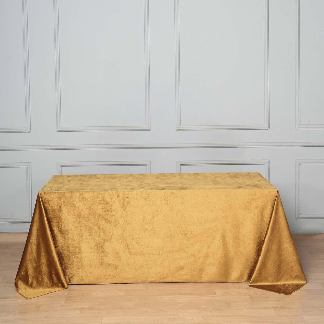 Gold tablecloth on a wooden table against a gray wall.