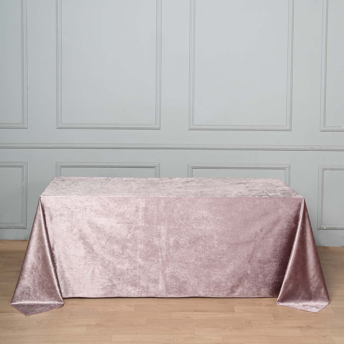 Pink velvet tablecloth on a wooden floor against a gray wall.