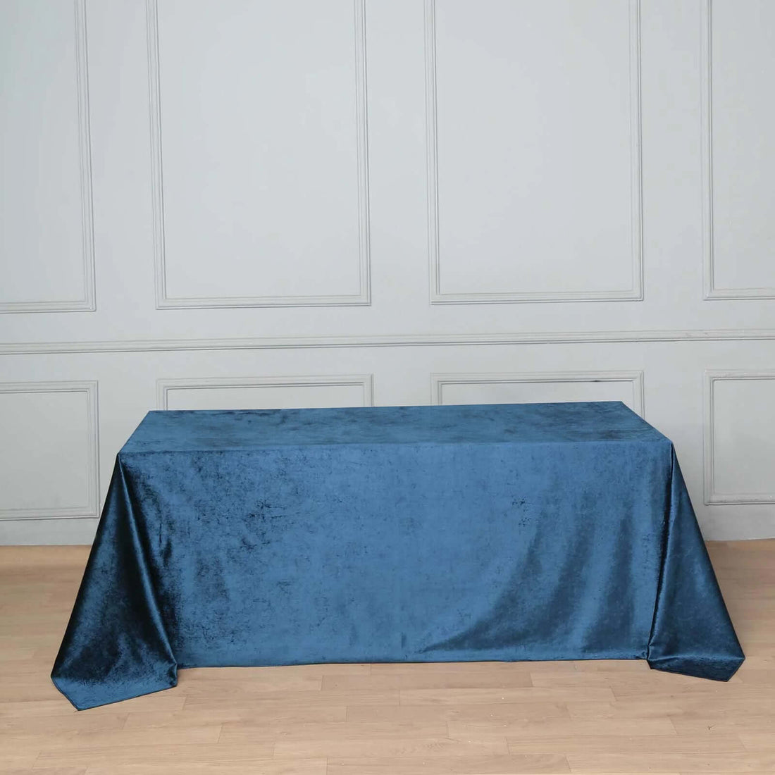 Blue velvet tablecloth on a wooden floor with a textured backdrop.