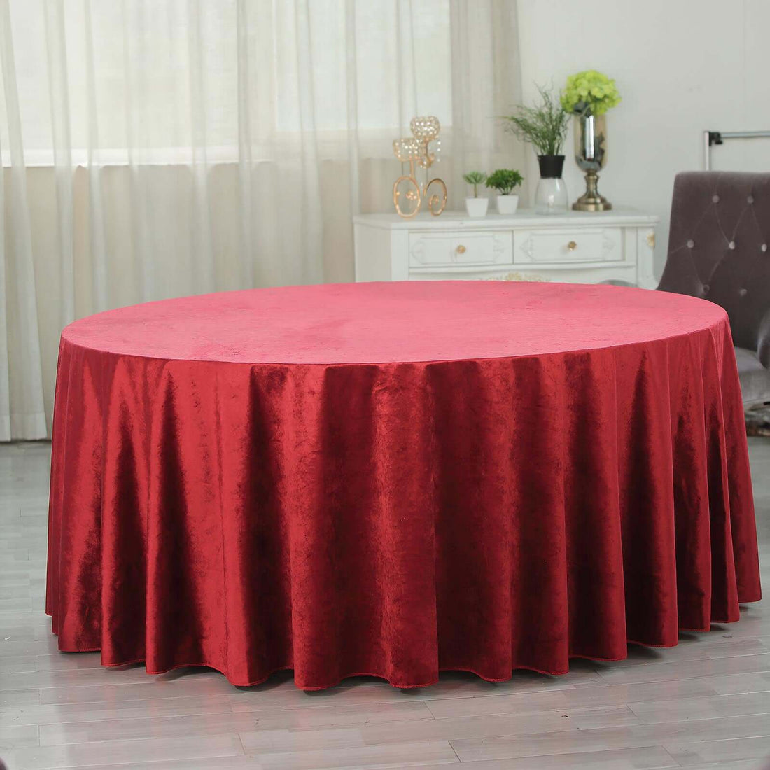 Red round tablecloth draped elegantly over a circular table in a bright room.