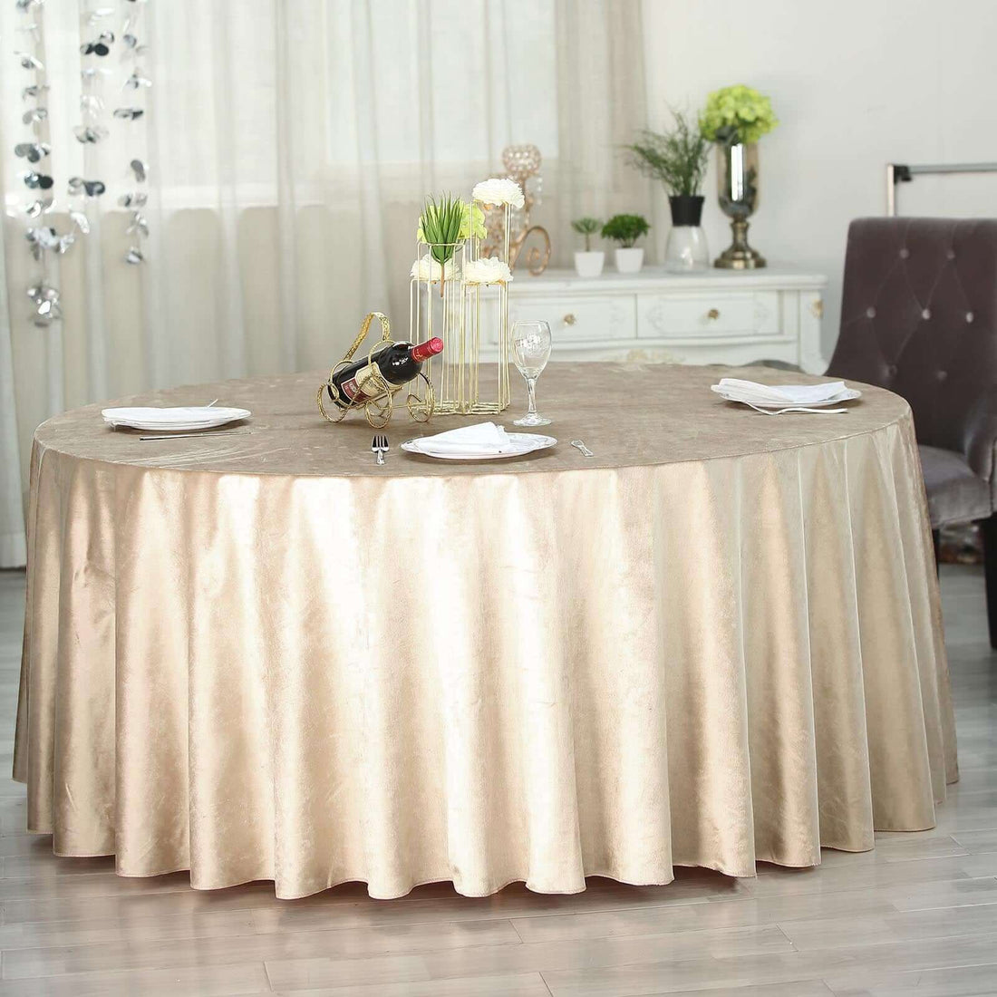 Elegant round table with beige tablecloth set for dining.