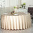 Elegant round table with beige tablecloth set for dining.