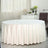 Round table covered with a white tablecloth in a bright, elegant room.