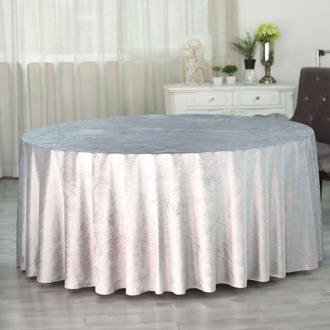 Round silver tablecloth with elegant draping for dining or events.