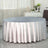 Round silver tablecloth with elegant draping for dining or events.