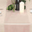 Elegant blush table runner styled with greenery and candle on a dining table.