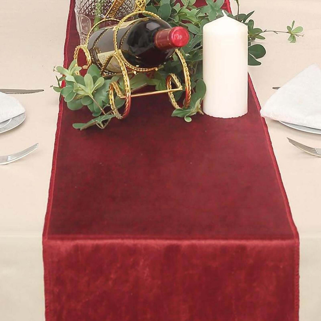Burgundy table runner with wine bottle and candle on a dining table setting.
