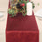 Burgundy table runner with wine bottle and candle on a dining table setting.