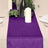 Purple table runner with candles and greenery on a dining table.